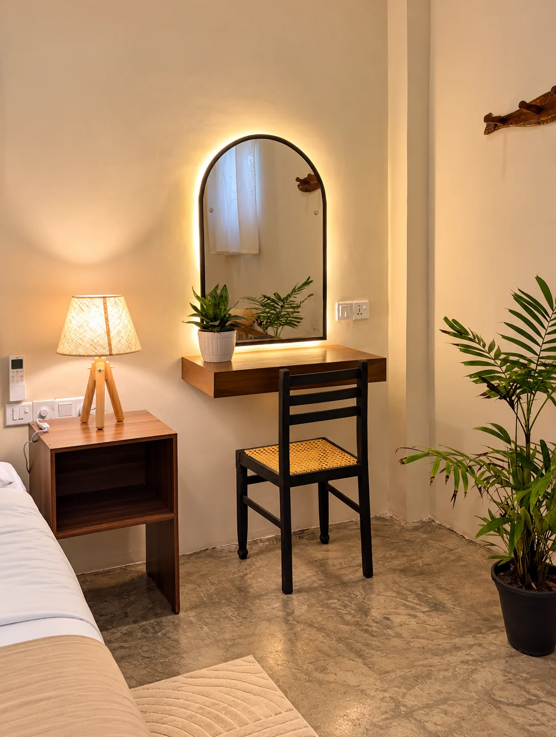 Bedroom dressing corner with a warmly lit arched mirror