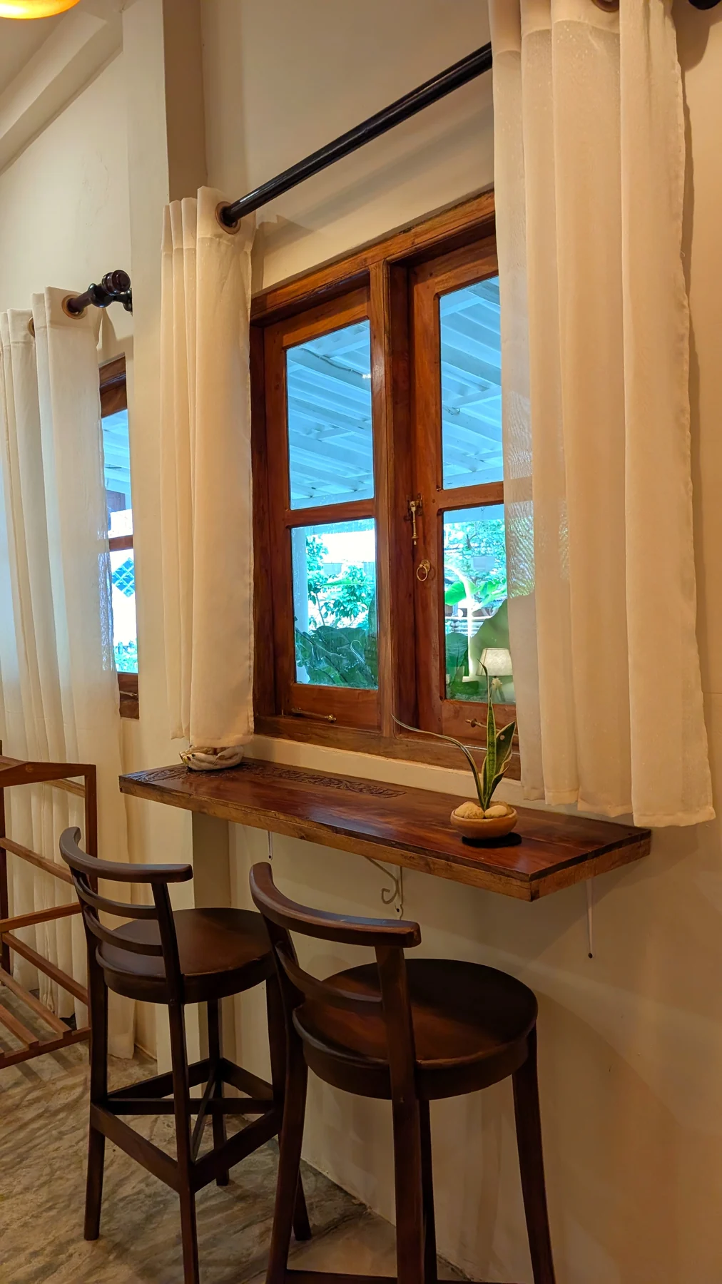 Window nook with a timber counter and stools overlooking the garden